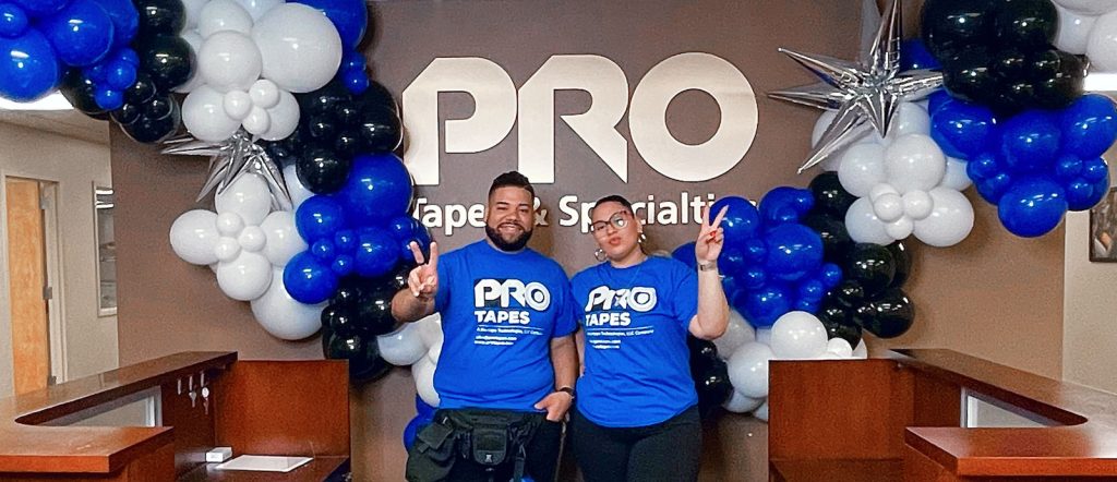 Dellon's balloon artists Dolly and Eddie, showcase a stunning blue, white, and black balloon garland created with Pro Tapes products at the Pro Tapes office.
