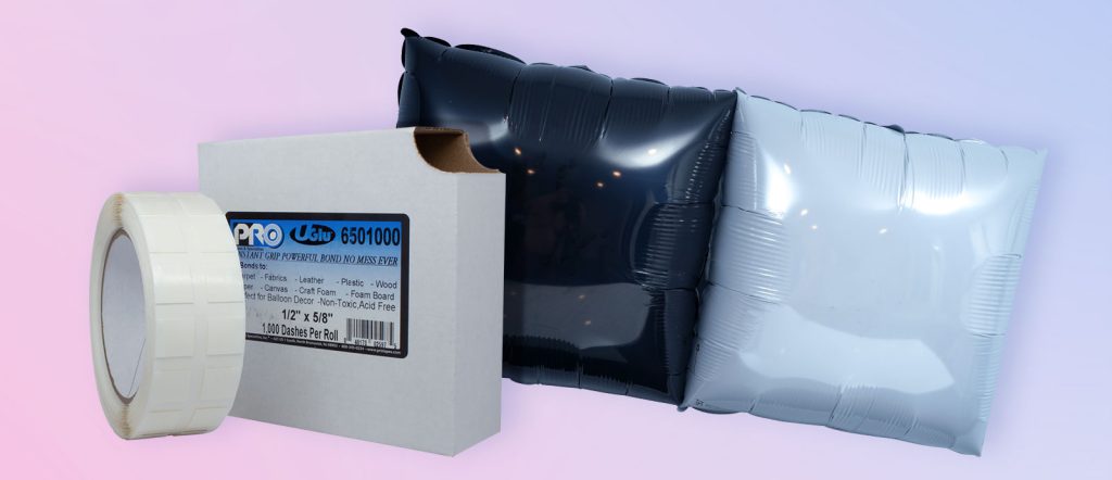 UGlu 650 Dispenser with roll in front of it. Next to the dispenser are foil balloons in the colors black and white.