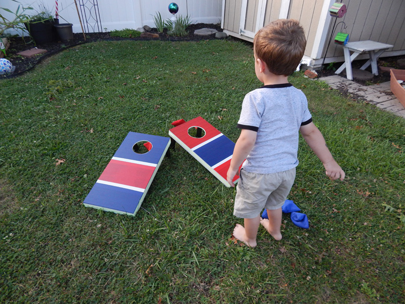 Becky's young son playing with the finished cornhole game boards.