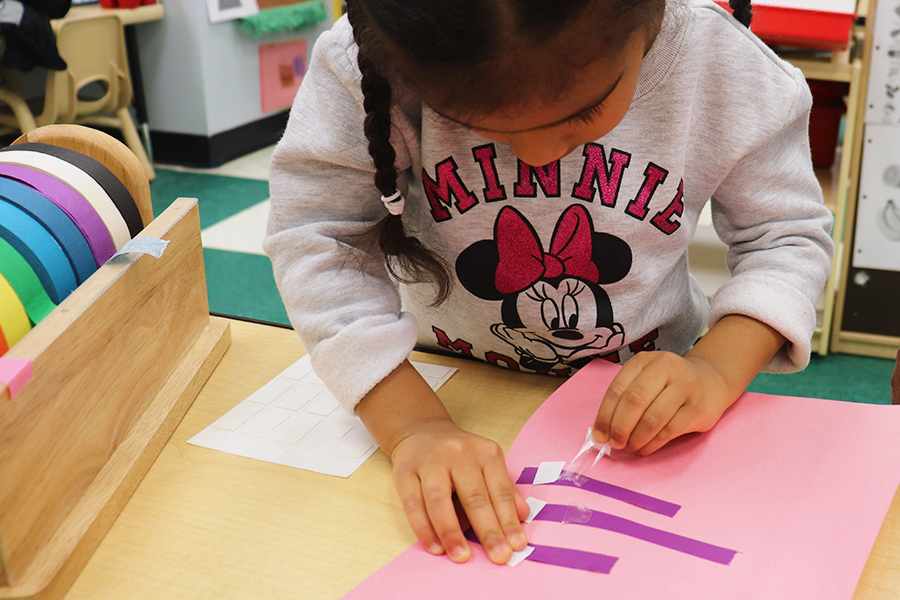 Developing fine motor skills by peeling and sticking tape.